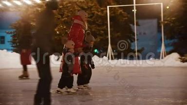 一家<strong>年轻</strong>的<strong>母亲</strong>和两个孩子<strong>牵</strong>着手在溜冰场上滑冰